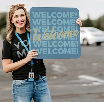 A woman holding a welcome sign